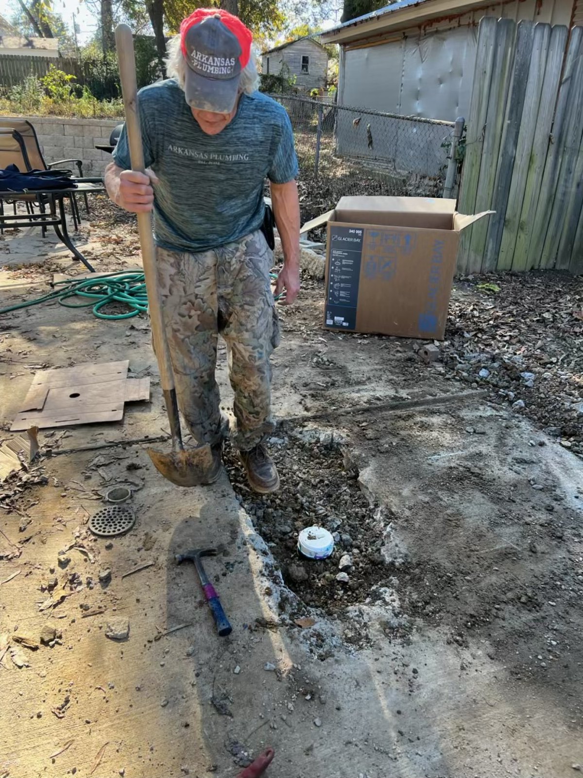Keith Walls with a shovel at a cut concrete cleanout in a backyard