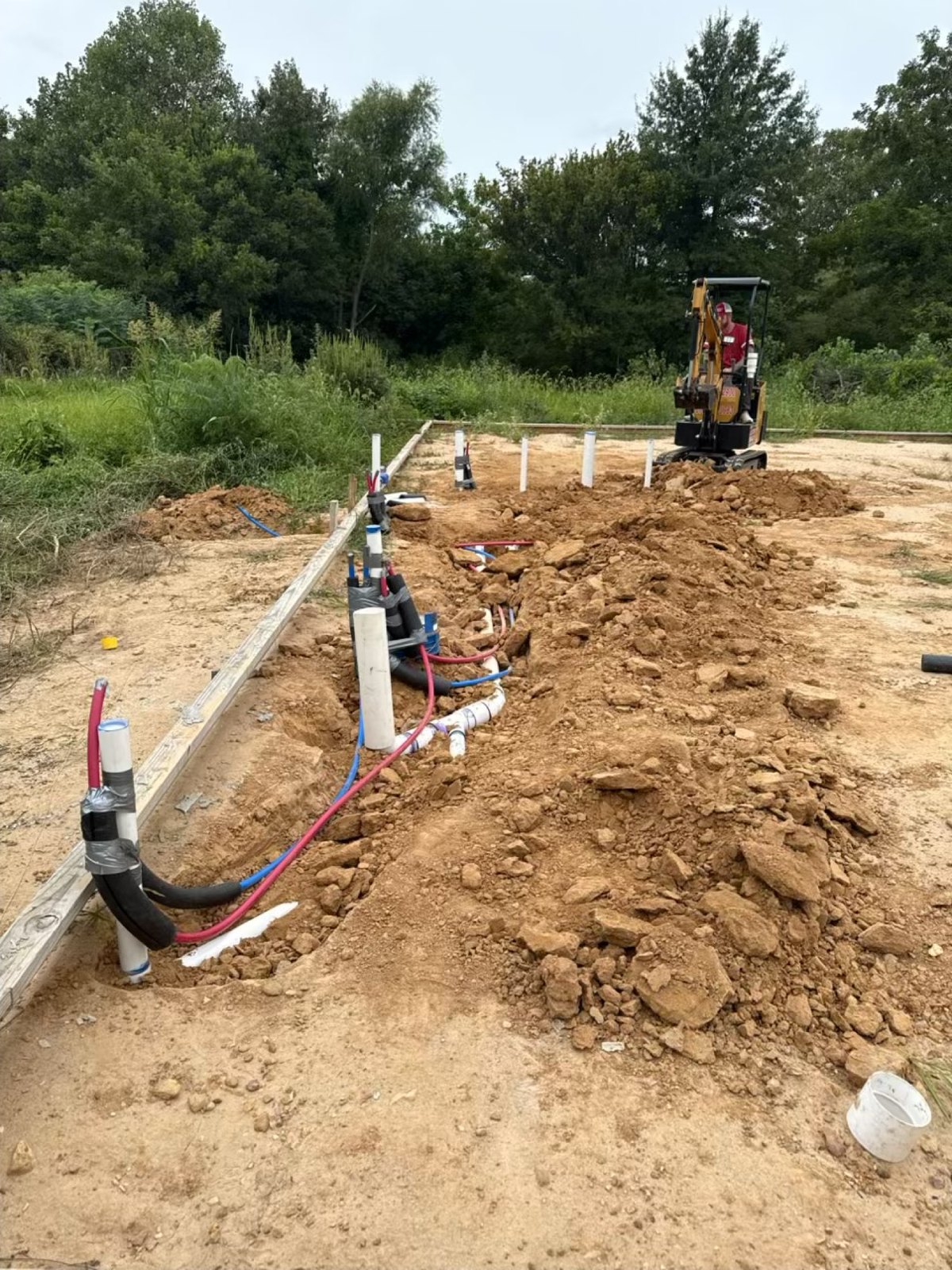 Underground plumbing rough-in with PEX, sewer, and the mini excavator on a new house pad