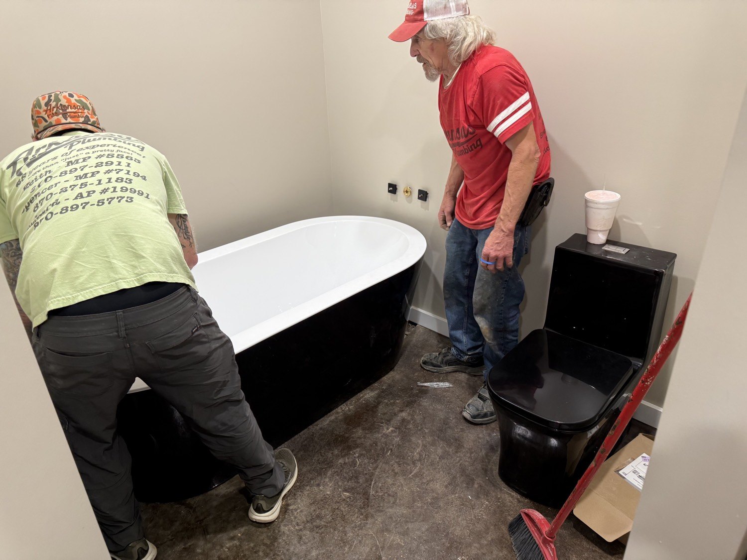 Richard and Keith setting a black freestanding tub next to a black toilet
