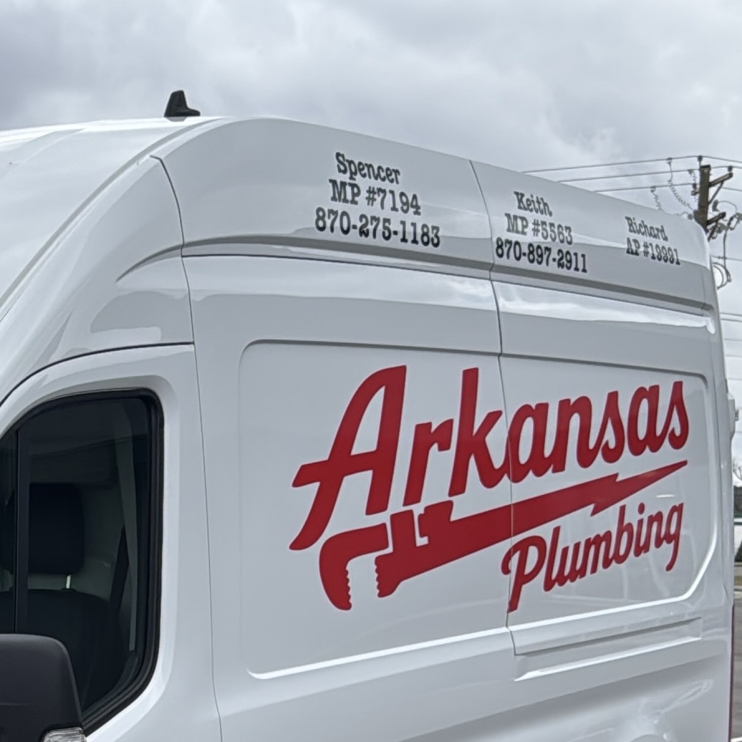 Arkansas Plumbing van — Spencer, Keith, and Richard on the roof line, script logo on the door