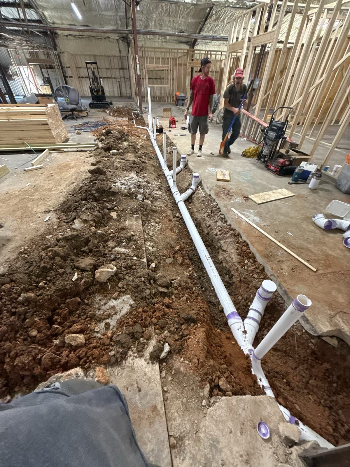 Richard and Keith on a commercial indoor sewer rough-in with PVC in an open trench